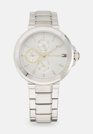 Montre en acier inoxydable argenté avec un cadran rond, un cadran gris clair, trois sous-cadrans, des index en cristal et un bracelet poli.