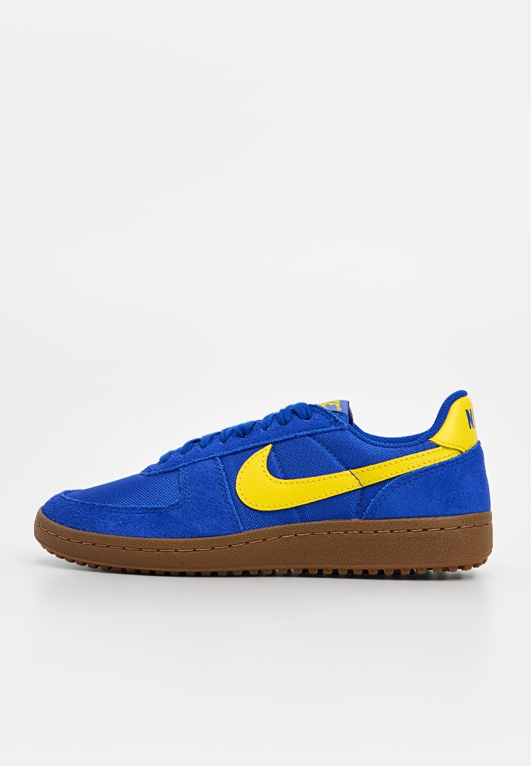 Blaue Wildledersneaker mit gelben Akzenten, ausgestattet mit einer braunen Gummisohle, runder Zehenform und strukturierten Oberflächen. Schnürdesign mit Logodetail.