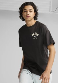 Sort bomulds T-shirt med et hvidt PUMA-logo og teksten "est. 48". Korte ærmer og rund halsudskæring, med et afslappet fit-design.