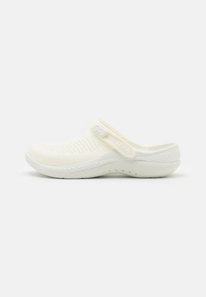 Weißer Clog aus flexiblem Material, mit perforiertem Design, verstellbarem Riemen und strukturiertem Boden für besseren Halt.