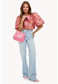 Blouse rose bouffante avec des motifs dorés, jeans taille haute bleu clair, sac à main pailleté rose et escarpins roses pointus.