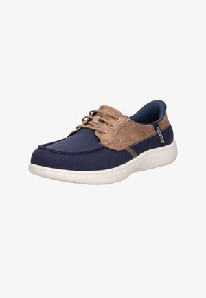 Marineblauwe en beige casual veter sneaker met witte zool, moc toe ontwerp en "Skechers Slip-Ins" label aan de zijkant.