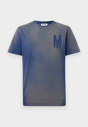 Plava-siva majica kratkih rukava s velikim tamnoplavim slovom "M" na lijevoj strani prsa i etiketom Moschino unutar ovratnika.