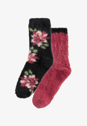 Une paire de chaussettes en peluche, l'une de couleur rose foncé uni et l'autre noire avec des motifs floraux roses et verts.
