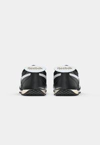 Crne atletske tenisice s bijelim detaljima, teksturiranom gumenom potplatom i podstavljenim okovratnikom. Na petnom dijelu se nalazi Reebok logo. Klasični dizajn.