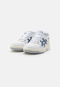 Baskets blanches en cuir avec des accents bleus, boîte à orteils perforée et semelles texturées. Dotées d'un design à lacets et d'un col rembourré.