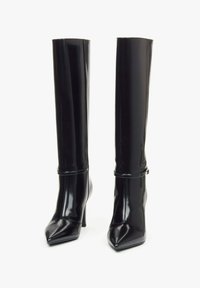 Černé kotníkové stiletto boty vyrobené z lesklého materiálu, s špičatou špičkou a tenkým detailem na kotníku. Hladký, přiléhavý design.