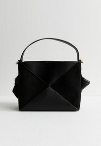 Bolso negro que presenta una mezcla de cuero texturizado y ante, de forma rectangular, con asa superior y un diseño plegado con costuras visibles.