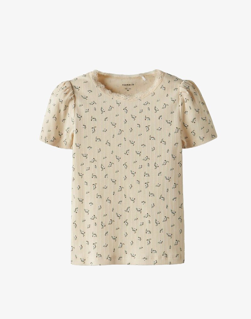 Gai dzeltena īsām piedurknēm krekls ar ribotu tekstūru, kas rotāts ar mežģīņu apdari ap apaļu kaklu un nelielu ziedu rakstu zaļā un baltā krāsā.