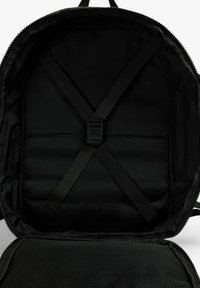 Interior de mochila negra con paredes acolchadas, correas ajustables y un bolsillo de malla. Cierre de cremallera con un acabado suave. Tejido texturizado.