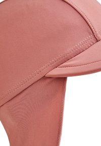 Rosa Kappe aus leichtem Material mit glatter Textur. Verfügt über einen strukturierten Schirm und gestickte Nähte für Langlebigkeit.