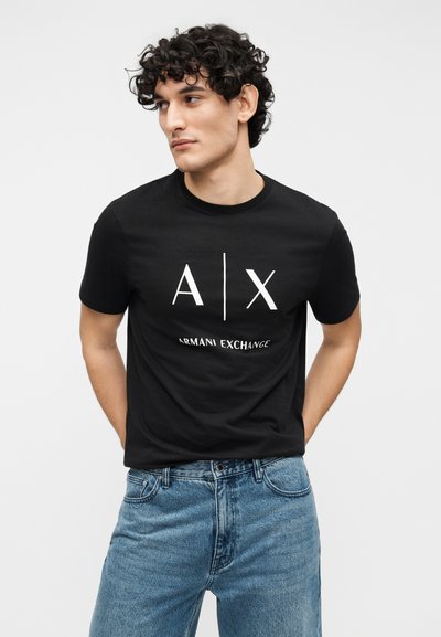 T-shirt noir en coton avec un logo blanc "A|X" et le texte "ARMANI EXCHANGE", accompagné d'un jean en denim bleu clair.