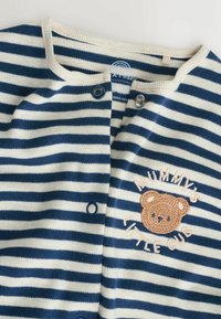Maglia a maniche lunghe a righe in navy e crema, con ricamo di un orso e chiusura a bottoni al collo. Tessuto morbido con dettagli a coste.