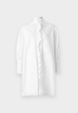 Hvid skjortedress med lange puffærmer, høj hals og dekorative flæser ned foran. Har teksturerede mønstre og blonder detaljer.