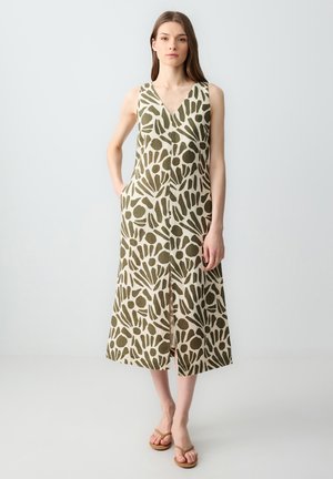 Mouwloze V-hals jurk in lichtbeige met een groen abstract patroon. Voorzien van een split aan de voorkant en zakken. Gemaakt van een lichte stof.