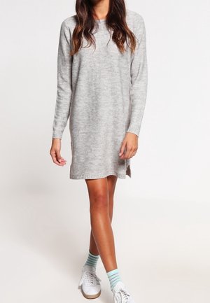 Abito a maglia grigio chiaro con maniche lunghe, spacchi laterali e vestibilità rilassata, abbinato a sneakers bianche e calzini a righe verde menta.