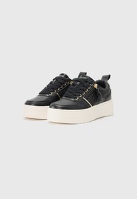 Schwarze Leder-Plateausneaker mit goldenen Akzenten, runder Zehenpartie, dicker weißer Sohle und strukturierten Details. Mit Schnürverschluss und Schlaufe zum Anziehen.