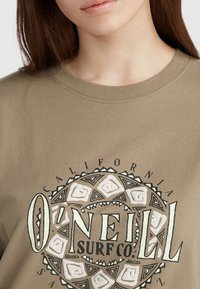 Olijfgroen katoenen t-shirt met een ronde afbeelding met tribale patronen en de tekst "O'Neill Surf Co." in zwart en roomkleurige tinten.