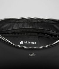 Interior de bolsa negra con cremallera que presenta una textura de nylon suave, cremallera plateada y una etiqueta de logo de lululemon. Compacta con dobles compartimentos.