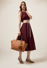 Rochie A-line de culoare vișinie cu o curea bej, asortată cu o geantă din piele tan și balerini gri cu fundiță. Texturi moi și delicate vizibile.