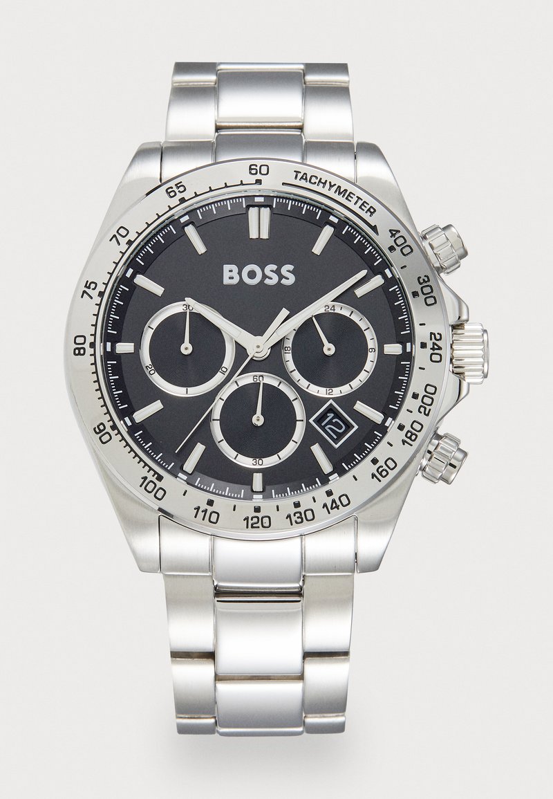 Ασημί ανοξείδωτο ατσάλινο ρολόι χρονογράφου με μαύρο καντράν, τρία υποκαντράν, κλίμακα ταχυμέτρου και ένδειξη ημερομηνίας. Διαθέτει έντονες λευκές ενδείξεις.