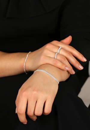 Silver smycken med två armband och en ring, alla prydda med klara ädelstenar som visar upp intrikata detaljer och en polerad yta.