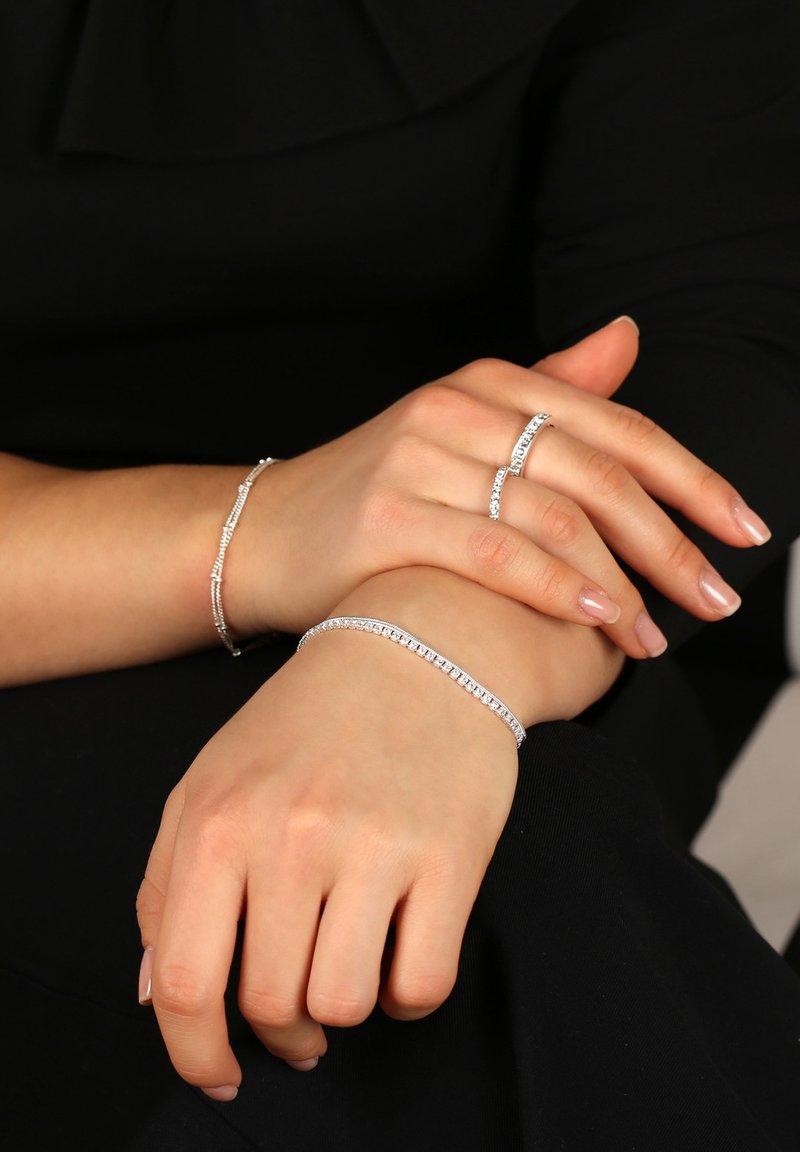 Silver smycken med två armband och en ring, alla prydda med klara ädelstenar som visar upp intrikata detaljer och en polerad yta.