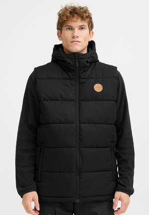 Black puffer vest with a hood, featuring a quilted design and a round tan leather logo patch. Front zipper and two side pockets.