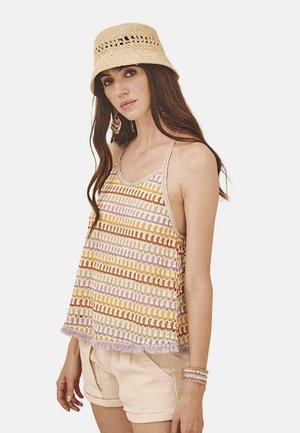 Top sin mangas de tela colorida con varios patrones horizontales en naranja, rosa y lavanda, combinado con pantalones cortos beige claros y un sombrero de paja.