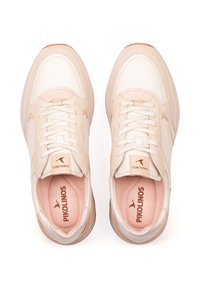 Zapatillas beige y crema con parte superior de cuero suave, lengüeta acolchada y cordones, que presentan una suela de color claro y un logo sutil.