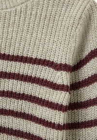 Pull en tricot beige clair avec de larges rayures bordeaux. La texture est lâche et aérienne, avec un col rond et des bords côtelés.