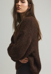 Brauner gestrickter Pullover mit lockerem Sitz, strukturierter Stoff und überschnittenen Schultern. Weiches und gemütliches Aussehen mit breiten, gerippten Bündchen.