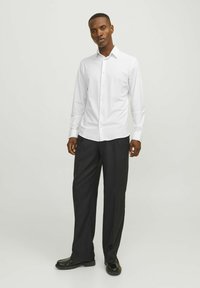 Camicia bianca a maniche lunghe con bottoni e pantaloni eleganti neri, caratterizzati da un colletto classico, una vestibilità dritta e un tessuto liscio con una leggera lucentezza.