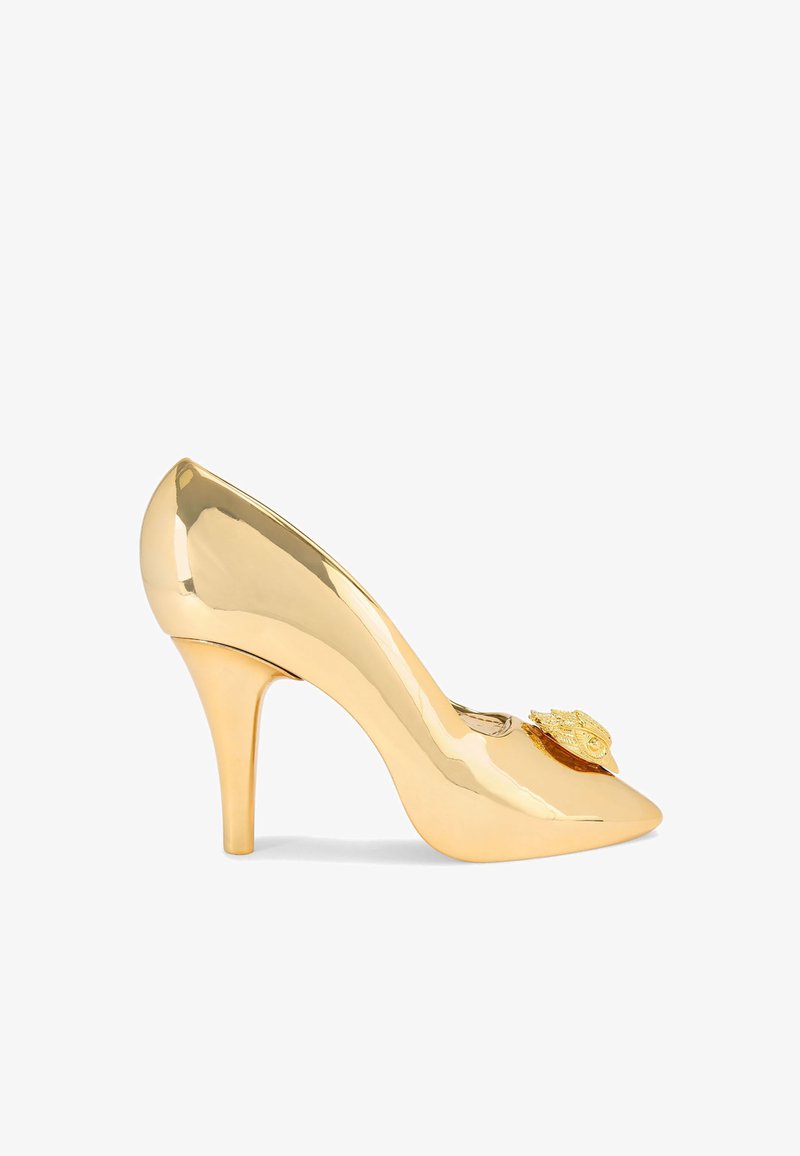 Escarpin en cuir patent doré avec un talon aiguille, une pointe fine et un emblème décoratif en or sur le dessus. Fini lisse et brillant.