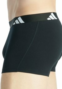 Pantaloni boxeur atletici neri con una texture liscia, elastico in vita con tre strisce bianche, vestibilità slim e senza loghi visibili.