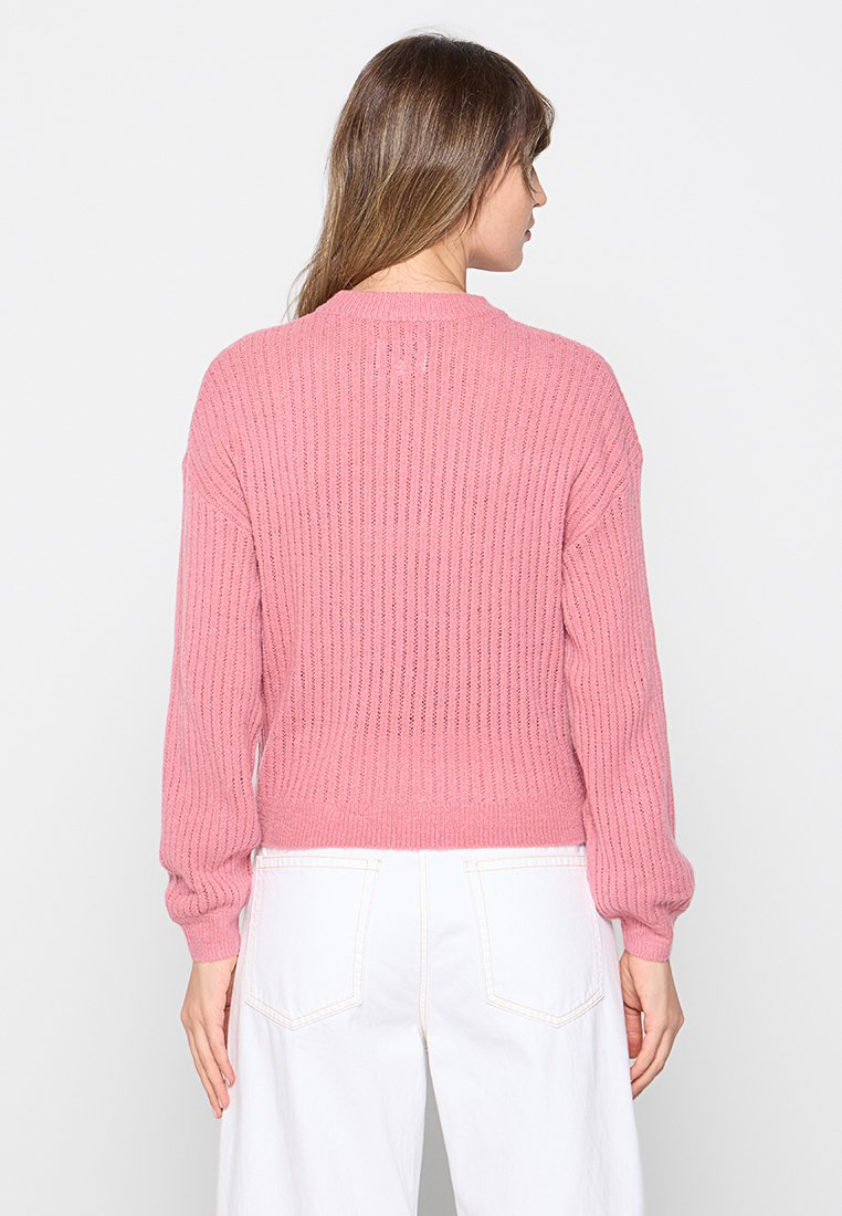 Różowy sweter z prążkowanego dzianiny o luźnym kroju, z długimi rękawami i skróconym dołem. Charakteryzuje się strukturalnym wzorem oraz okrągłym dekoltem.