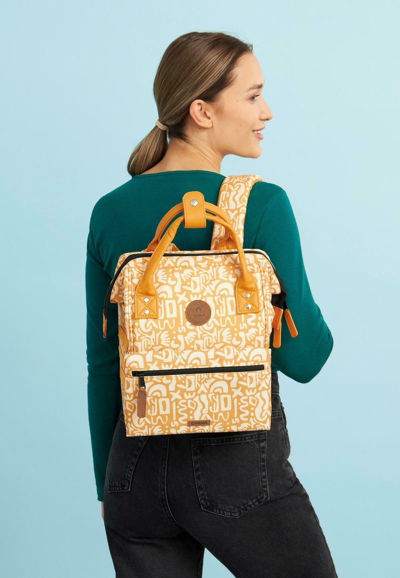 Rucksack in Orange und Creme mit grafischem Muster, ausgestattet mit einem oberen Griff, verstellbaren Trägern und einer Vorderreißverschlusstasche.