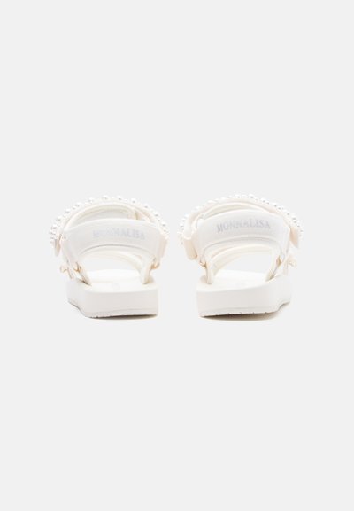 Λευκά σανδάλια με πλατφόρμα, ρυθμιζόμενα λουράκια και διακόσμηση με πέρλες, από πίσω σε λευκό απλό φόντο.