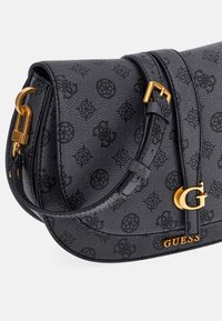Borsa in finta pelle nera con motivo a logo in rilievo, dettagli in hardware dorato, tracolla regolabile e un evidente dettaglio con logo "G" dorato.