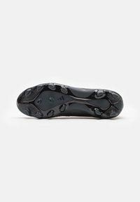 Suola di scarpa sportiva nera con superficie texturizzata e con stud circulari per trazione e durata, e un logo del marchio al centro.