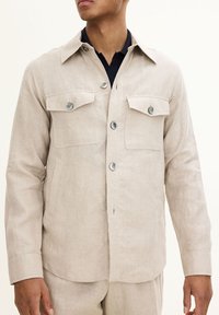 Lysbrun linned skjortejakke med krave, lange ærmer, to brystlommer og frontknapper, der har en afslappet pasform og minimal tekstur.