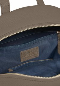 Interior de un bolso de cuero gris con cremallera, forro de tela azul y un pequeño bolsillo con cremallera. Presenta una etiqueta con "Lazarotti" embellecida.