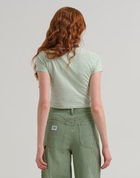 T-shirt cropped a righe verdi e bianche con maniche corte. Abbinato a pantaloni a vita alta a righe verdi e bianche con tasche posteriori.