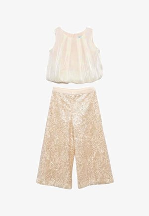 Top smanicato color crema plissettato abbinato a pantaloni a vita alta, a gamba larga, in pizzo beige con intricati motivi floreali.