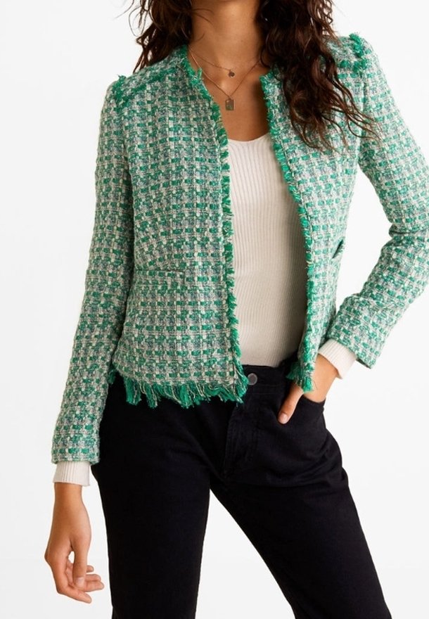 Femme portant un blazer texturé à carreaux verts et blancs par-dessus un top blanc côtelé, associé à un pantalon noir taille haute.