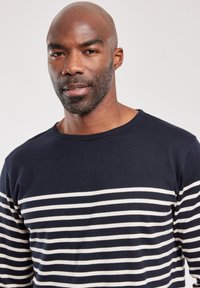 Mørkeblå langærmet skjorte med vandrette hvide striber. Har en rund halsudskæring og tekstureret stof. Minimalistisk design uden pynt.