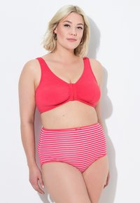 Czerwony biustonosz bikini z szerokimi ramiączkami i detalem w postaci kokardy na środku, w połączeniu z wysokim pasek w paski w kolorze różowym i białym. Gładka faktura materiału.