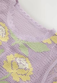 Tissu crocheté lavande avec bord festonné, présentant des motifs floraux jaunes et blancs et des feuilles vertes sur un fond en maille.