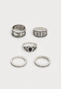 Ensemble de cinq bagues en argent présentant divers designs : motifs gravés, une pierre noire centrale, des surfaces texturées et des largeurs différentes.