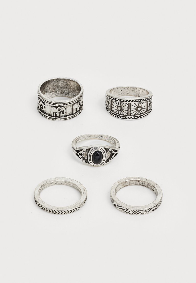 Ensemble de cinq bagues en argent présentant divers designs : motifs gravés, une pierre noire centrale, des surfaces texturées et des largeurs différentes.